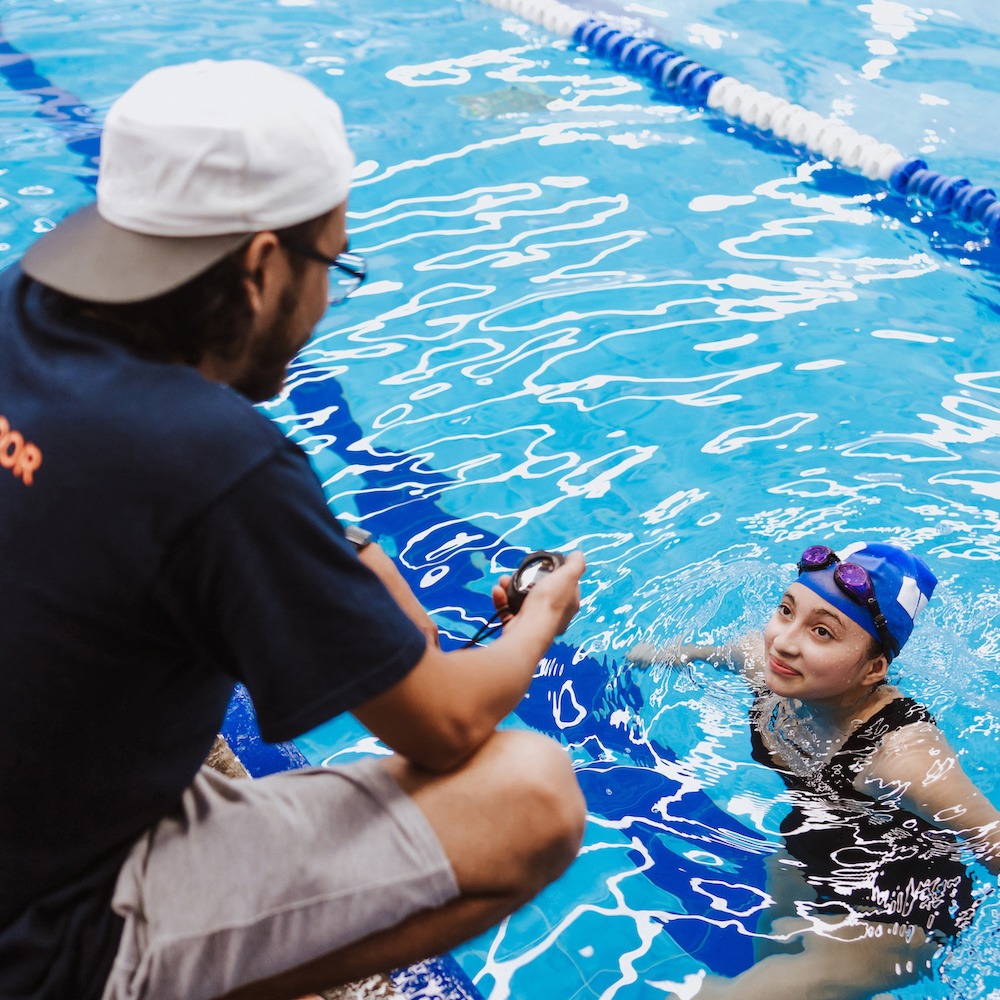 female swimmer in pool listening to swim instructor crop